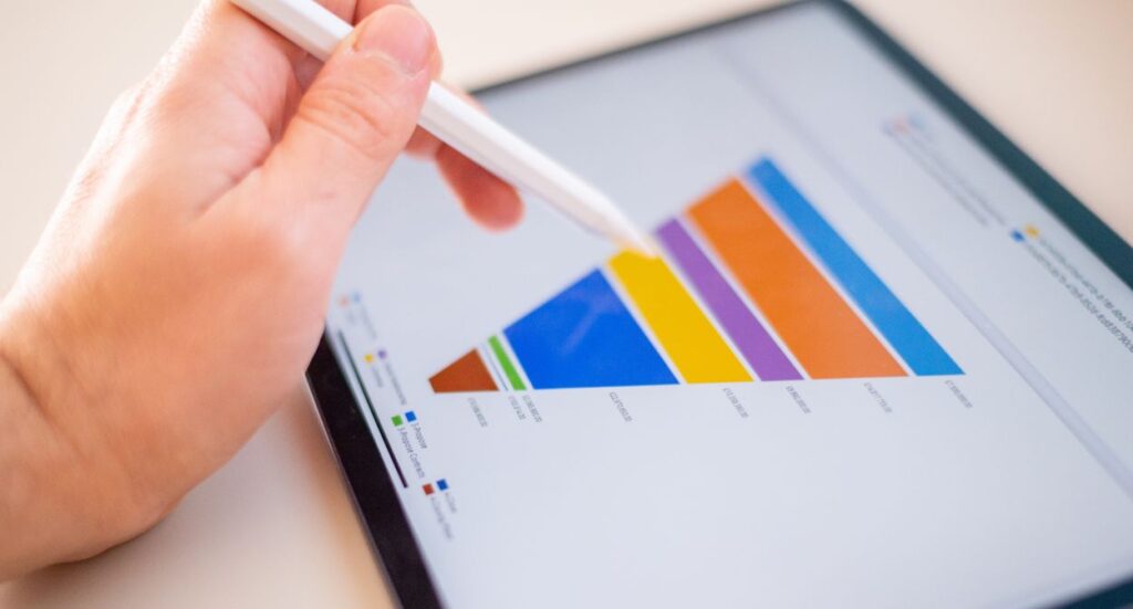 A person uses a stylus on a tablet displaying a colorful funnel chart with labeled sections, representing different stages or categories of data.