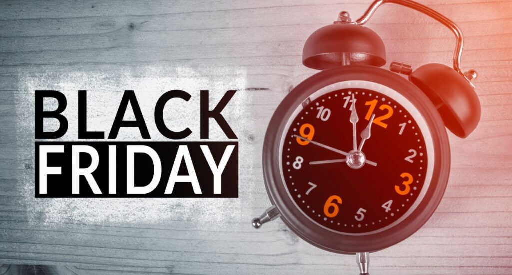 An old-fashioned black alarm clock next to bold text that reads Black Friday on a wooden surface, suggesting urgency for Black Friday deals.