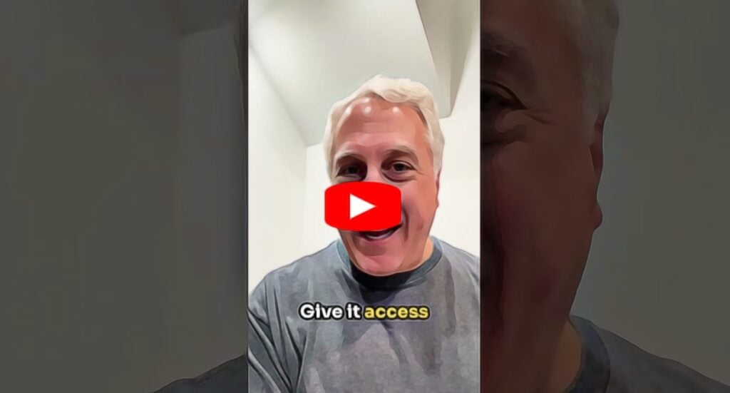 A man with gray hair and a gray shirt is smiling at the camera in a well-lit room. The text “Give it access” appears at the bottom, and a red play button icon is overlayed in the center.