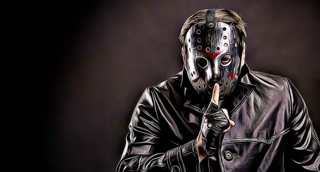 A person wearing a black and silver hockey mask and a dark leather jacket holds a gloved finger to their lips, signaling for silence against a dark background.